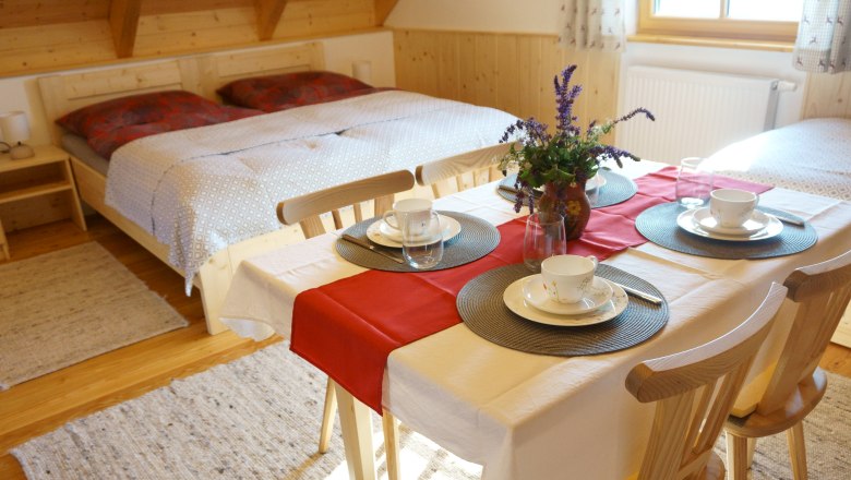 Gemütliches Zimmer mit Doppelbett und Esstisch, gedeckt für vier Personen.