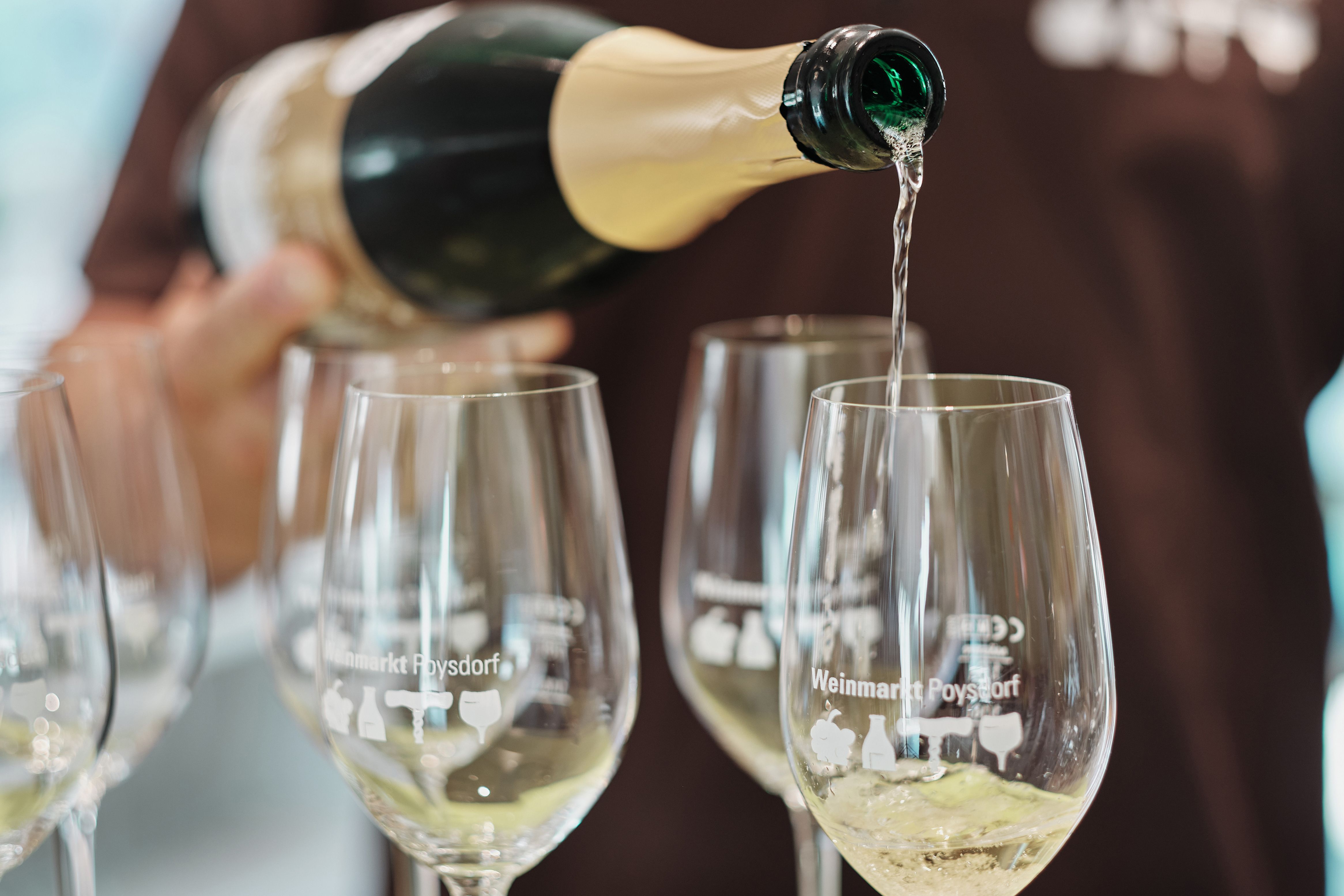 Aus einer Flasche wird Sekt in Gläser gefüllt.