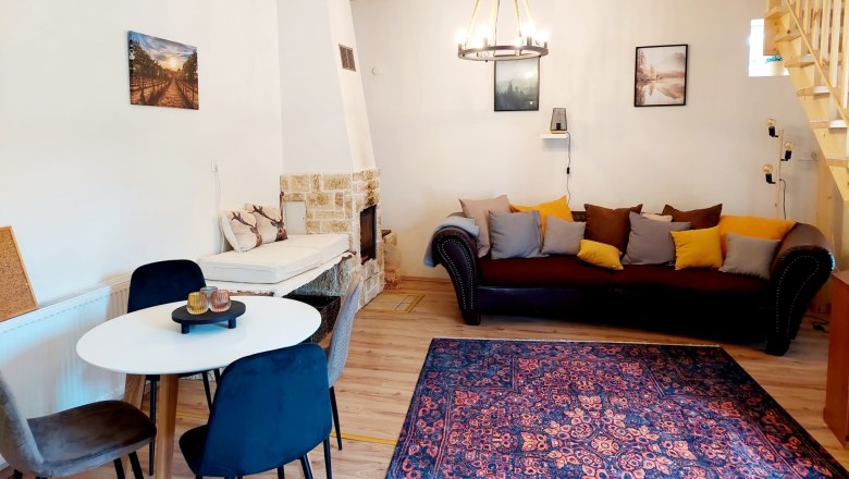 Gemütliches Wohn-Esszimmer mit Holzbalken, Sofa, Esstisch und Kamin.