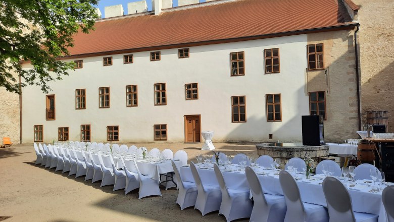 Langer, festlich gedeckter Tisch im Innenhof eines historischen Gebäudes.