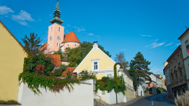 Straße in Poysdorf mit Kirche im Hintergrund und blauen Himmel.