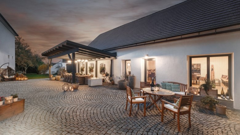 Gepflasterter Innenhof mit Tischen und Stühlen, umgeben von Gebäuden bei Abenddämmerung.